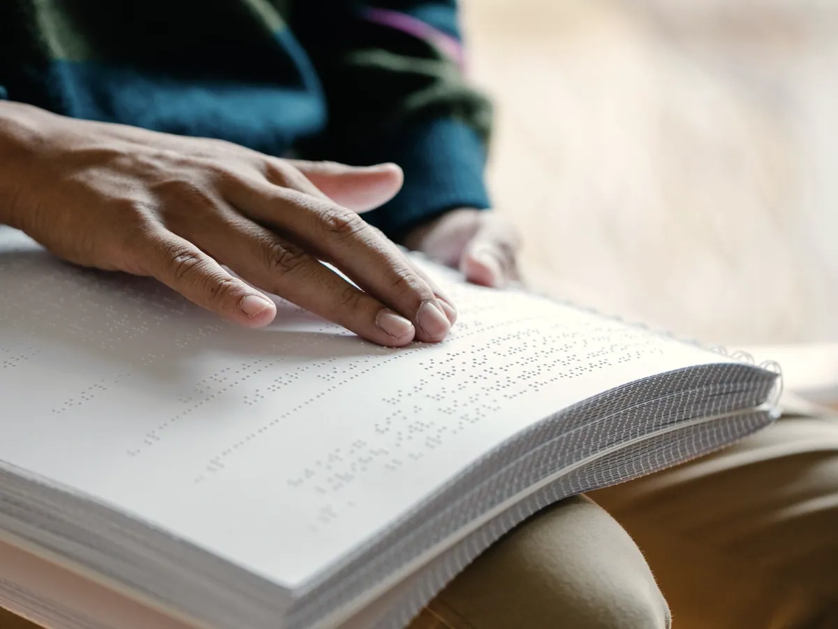 A hand reading a line of braille